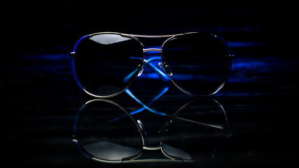 Fototapeta na wymiar Blue sunglasses on glass with reflection