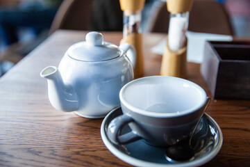 Teapot and cup and saucer on the table in the restaurant