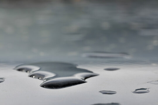 closeup of water droplets on the hood of a vehicle after a rainstorm