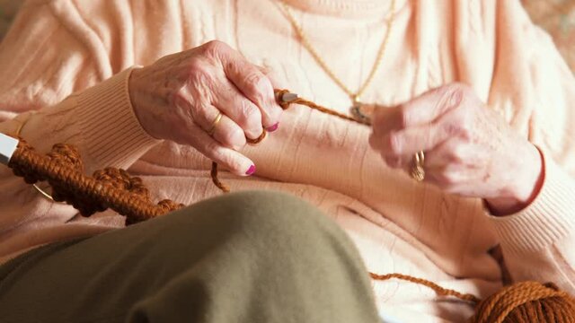 Grandmother knitting. Caucasian old woman hands slowly knitting, with difficulties because of her age