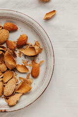 Almonds in a shell in a ceramic plate on a white background. Top view, close-up.