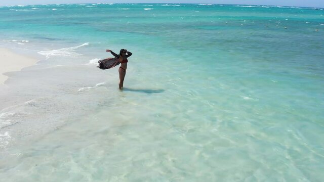 Solo woman in bikini on idyllic white sand beach at Playa Teco Maimon, Dominican Republic