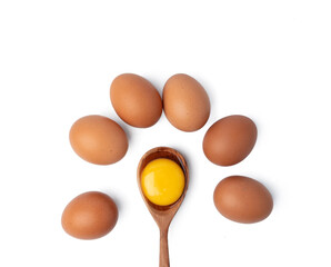 Brown eggs and egg yolk in wooden spoon on white background