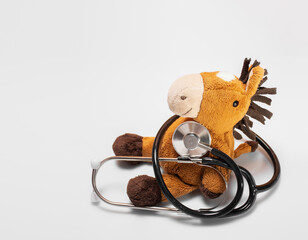 Stethoscope or phonendoscope with a plush toy on a white background: pediatric cardiology, blood donor for children. Banner of Health and Medicine