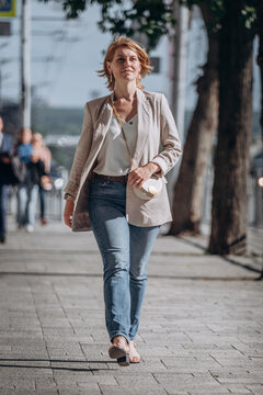 Young stylish woman walking in street. Woman wearing trendy coat, fashion shoes and holding black handbag. Fashion female blooger going. Fashion, lifestyle