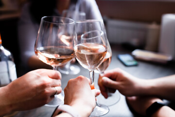 Friends raise glasses of wine at a home party. Russia, Front view.