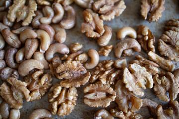 roasted cashews and walnuts on a baking sheet. Protein, harm or benefit of nuts. A mix of peeled...