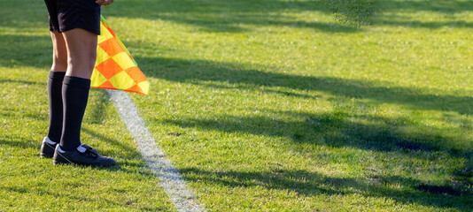 Football soccer arbiter assistant with flag at hands. Blurred green field background