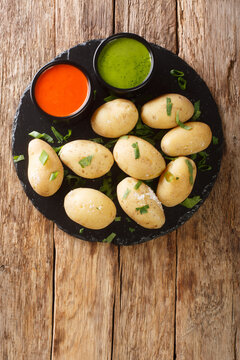 Papas arrugadas wrinkly potatoes is a traditional boiled potato dish served with a mojo rojo and mojo verde sauces close up in the plate on the table. Vertical top view from above