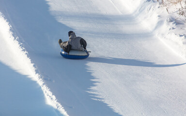 The boy rolls down the mountain on a tubing