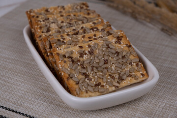 grain cracker, rectangular bread or cookies with seeds and different seeds on a white plate close-up