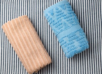 Two colored twisted towels on a striped background. Top view.