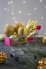 Christmas creative minimal composition. Shopping cart with Xmas 
gold decorations