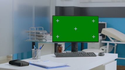 Empty hospital office equipped with mock up green screen chroma key computer with isolated display standing on table. Medical workplace with nobody in it offering medicine services