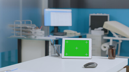 Mock up green screen tablet computer with isolated display standing on table in empty hospital...