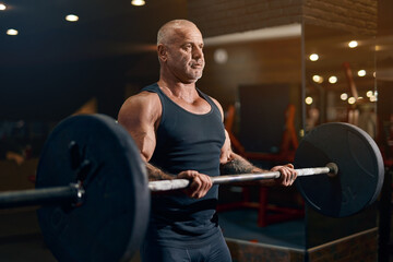 Fototapeta na wymiar adult sportsman pumping up biceps muscles while workout in gym with barbell. bodybuilding concept