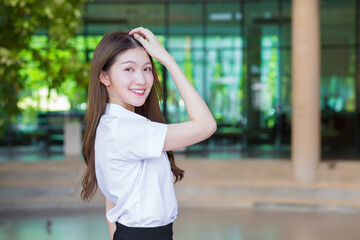 Portrait of an adult Thai student in university student uniform. Asian beautiful girl standing smiling happily looking at camera in university