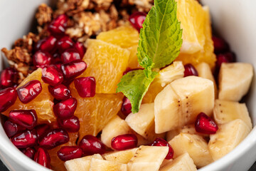 Closeup on sweet granola breakfast with banana pommegranate and oranges