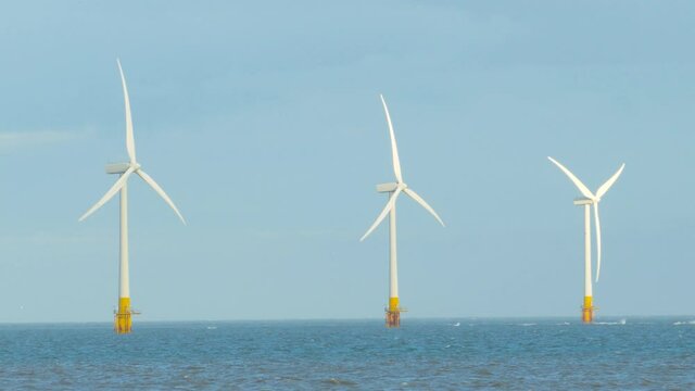 Scroby Sands Windmill Farm at sea coast of Great Yarmouth, England - static shot with sea water, wind turbine and clear sky 