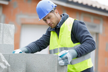builder man holding concrete blocks for house building