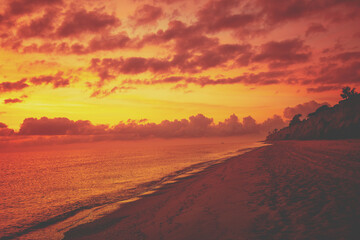 Obraz na płótnie Canvas Red orange blazing cloudy sky over the sea at sunset