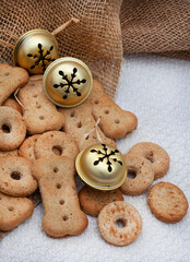 Different shapes of dog treat biscuits on light and neutral tabletop with Christmas ornaments