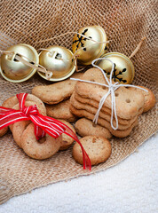 Different shapes of dog treat biscuits on light and neutral tabletop with Christmas ornaments