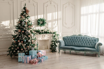 New Year's gifts in designer paper and bright ribbons under the Christmas tree on the floor on New Year's Eve. Christmas tree decorated with toys stands near the fireplace