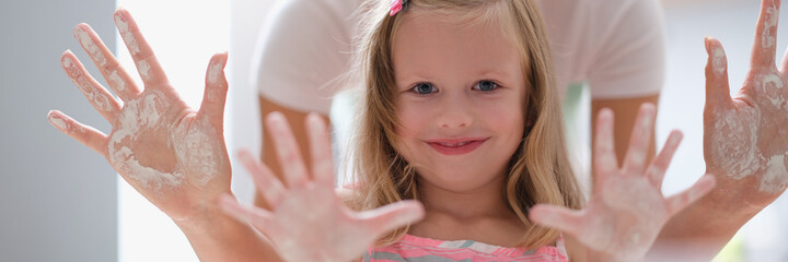 Mom and little girl showing palms of hands in flour