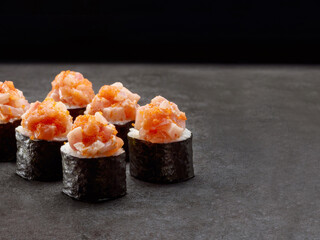 Japanese Maki sushi roll. Asian dish pieces with salmon and rock fish on top on dark concrete background. Copy space image. Single object. Inside out sushi
