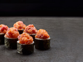 Japanese Maki sushi roll. Asian dish pieces with salmon and tuna on top on dark concrete background. Copy space image. Single object. Inside out sushi

