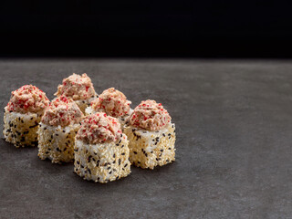 Japanese Sake sushi roll. Asian dish pieces with roasted salmon on top on dark concrete background. Copy space image. Single object. Inside out sushi
