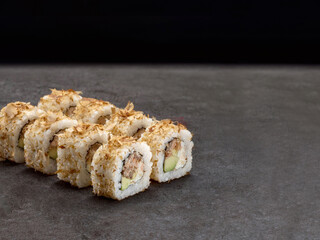 Japanese sushi roll with roasted salmon and avocado inside roll. Asian dish pieces with tuna chips Bonito on dark concrete background. Copy space image. Single object
