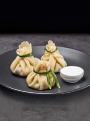 Russian traditional dish Blini. Appetising flat pancakes filled with chicken, mushrooms and green onions. Served with sour cream. Three Russian crepes on black plate
