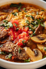 Closeup on bowl of korean beef ramen noodle soup with mushrooms