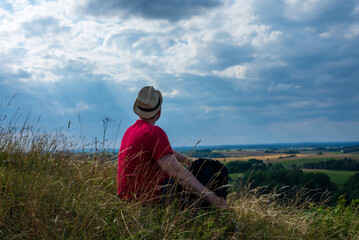 Naklejka na ściany i meble Young man admiring beautiful view of the forest landscape rear view.Young man standing alone summer day outdoors.