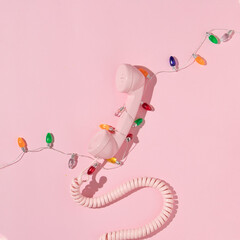 Christmas and New Year creative layout with pink retro phone handset and christmas lights...