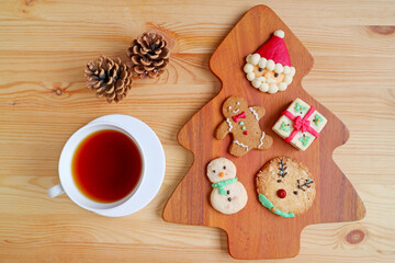Top View of Assorted Christmas Cookies with a Cup of Hot Tea and Dry Pine Cones Served on Wooden Table