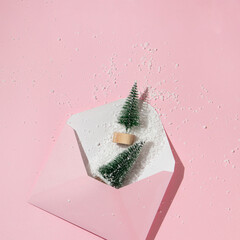 Christmas tree with snow in envelope on pastel pink background. Winter creative idea. Retro...