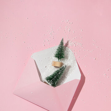 Christmas tree with snow in envelope on pastel pink background. Winter creative idea. Retro aesthetic christmas minimal concept.