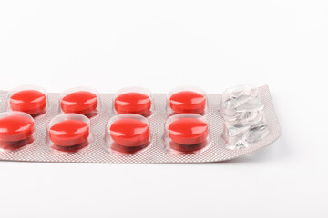 Isolated red pills in foil blister pack on a white background. Pharmacy. Treatment.