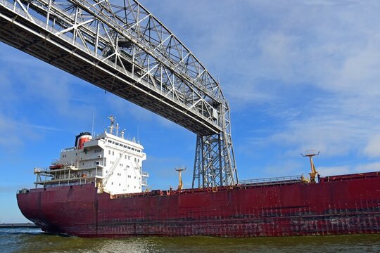  a saltie freighter from quebec passes  under the aerial lift bridge from lake superior into duluth harbor  on a sunny fall day in duluth, minnesota 