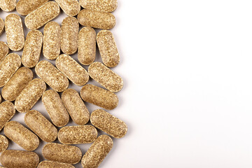 Nutrition supplements, brown vitamin pills on white background.