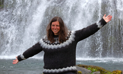 Woman in traditional Icelandic sweater enjoying the Icelandic landscape, the waterfall Dynjandi