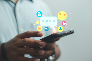 Social  and digital online concepts young man using a smartphone to play social media with smiley icon
