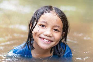 Close up portrait of happy Asian kid playing in water outdoor