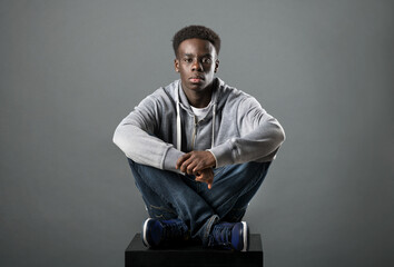 Young Black man posing cross-legged in a studio