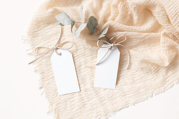 White gift tags mockup with eucalyptus branch on beige background 