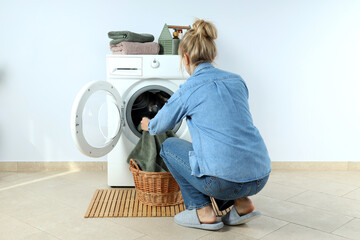 Concept of housework with washing machine and girl against white wall