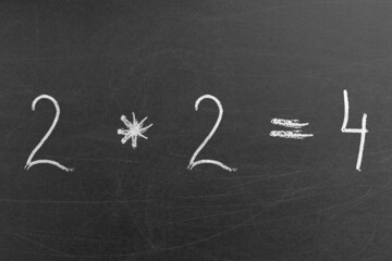 Simple math multiplication equation on the chalkboard with 2 and 4 numbers. Handwriting formulas...